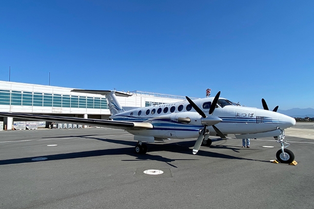 Aircraft:A white experimental propeller plane is on the airfield.